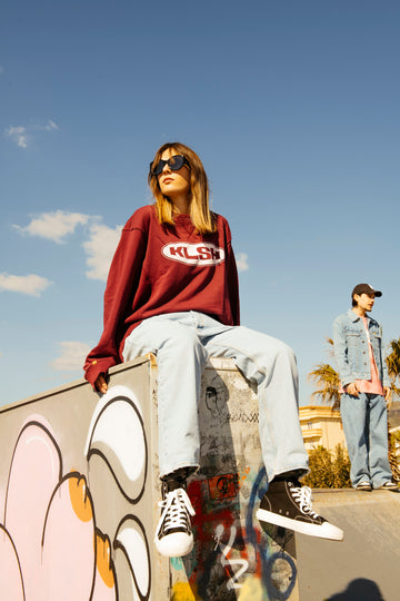 Person dressed in faded KLSH blue jean with a KLSH top