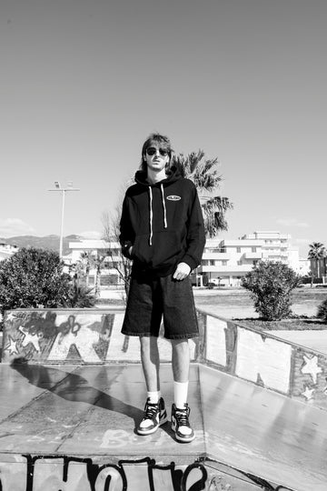 Person standing on a skateboard ramp with a cityscape in the background