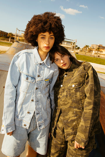 Two people standing close together outdoors with a clear sky.