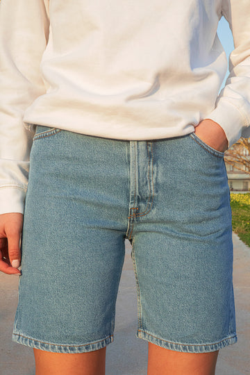 Person wearing blue denim shorts with a blurred background