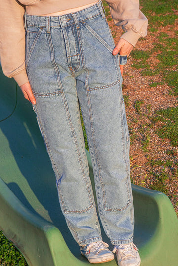 Person wearing blue jeans standing on a green slide outdoors