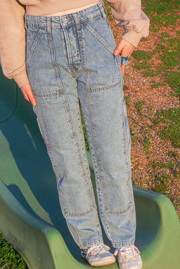 Person wearing blue jeans standing on a green slide outdoors
