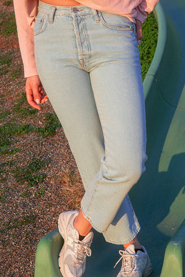 Person wearing the KLSH RYAN clear sky jeans and white sneakers on a green surface.