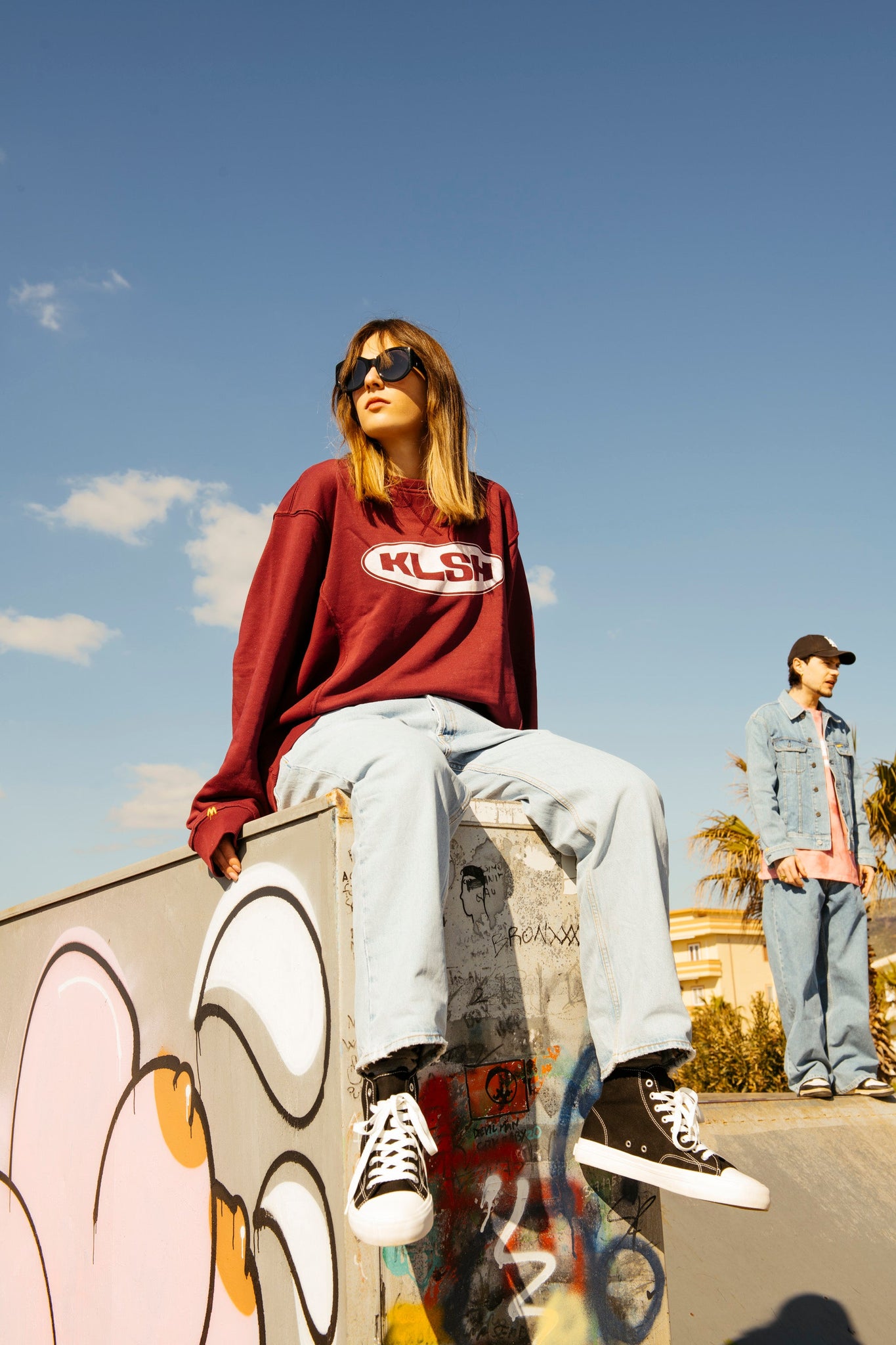 Person dressed in faded KLSH blue jean with a KLSH top