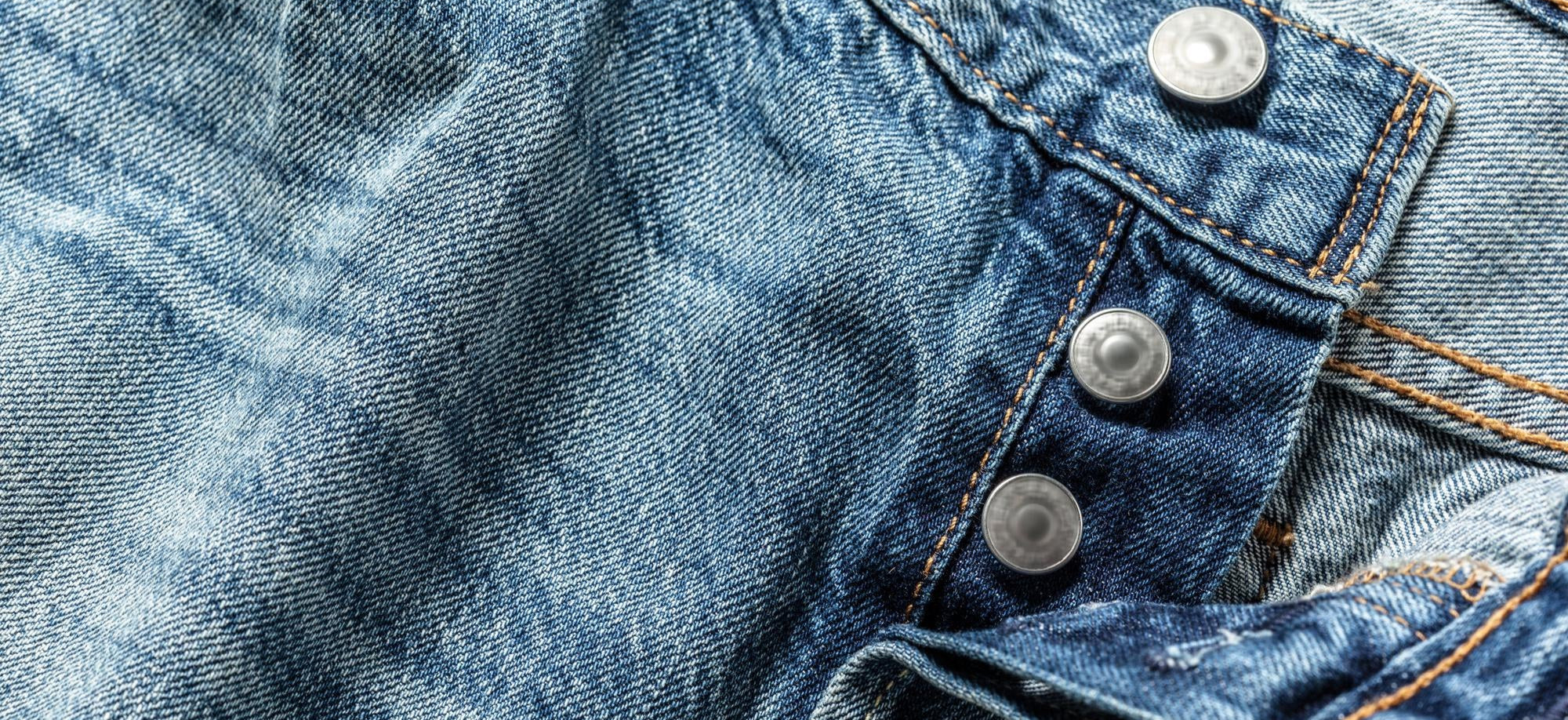 Close-up of blue denim fabric with buttons and stitching detailsslider_item_nMhWc7