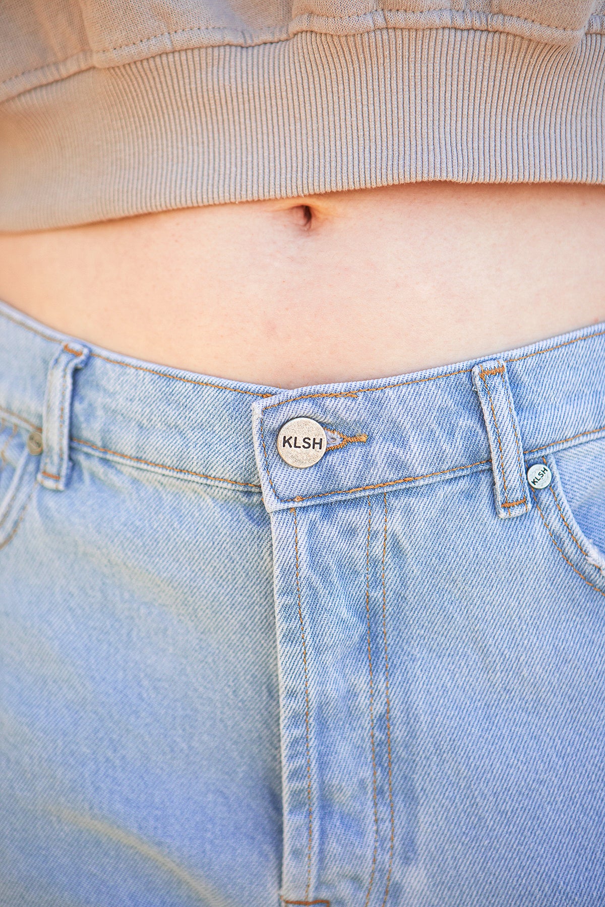 Clear sky jeans with KLSH brand label on the waistband, showing a cropped top.