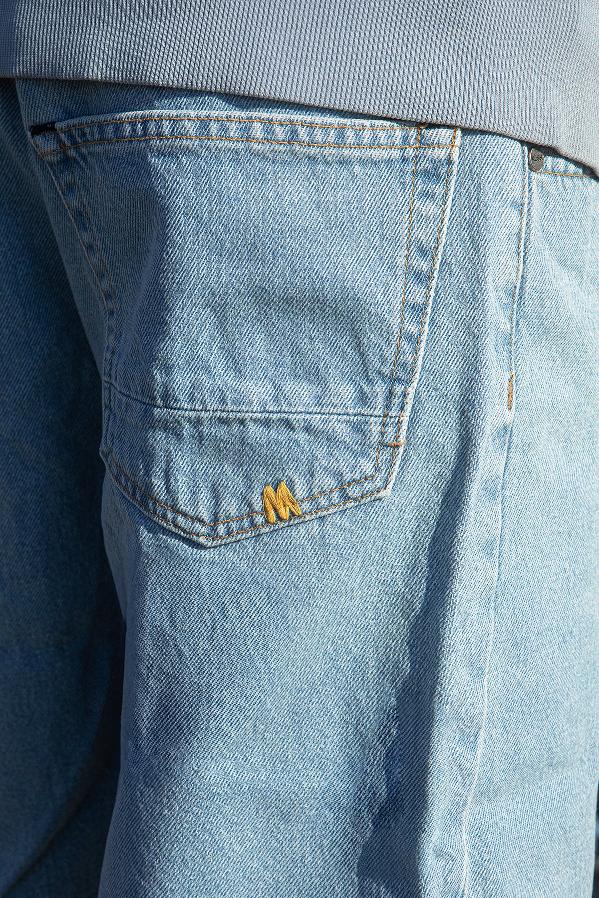 Close-up of a blue denim pocket with a brand logo.