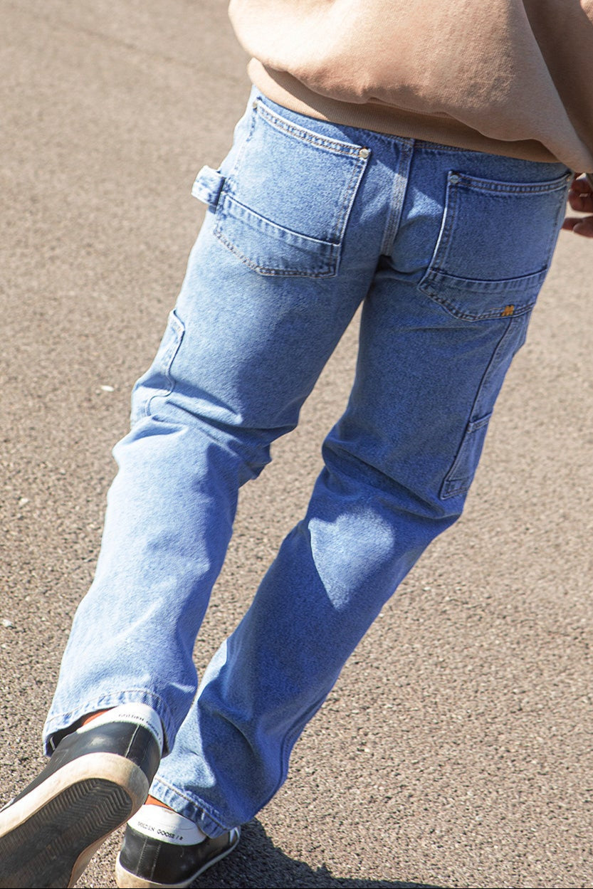 Person wearing work pant blue jeans on a concrete surface