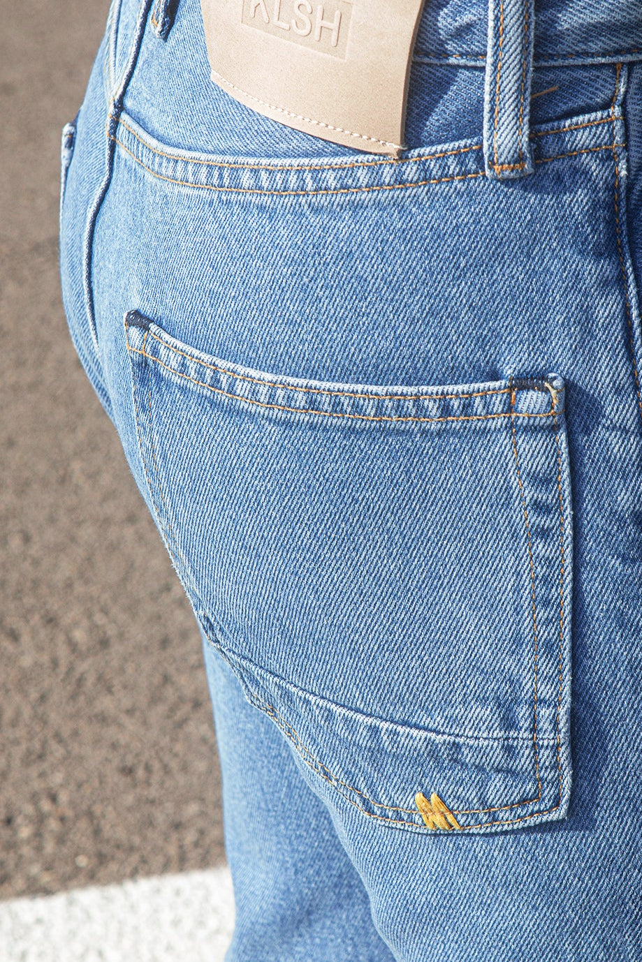 Close-up of the KLSH RYAN faded blue jeans with a brand label on a neutral background