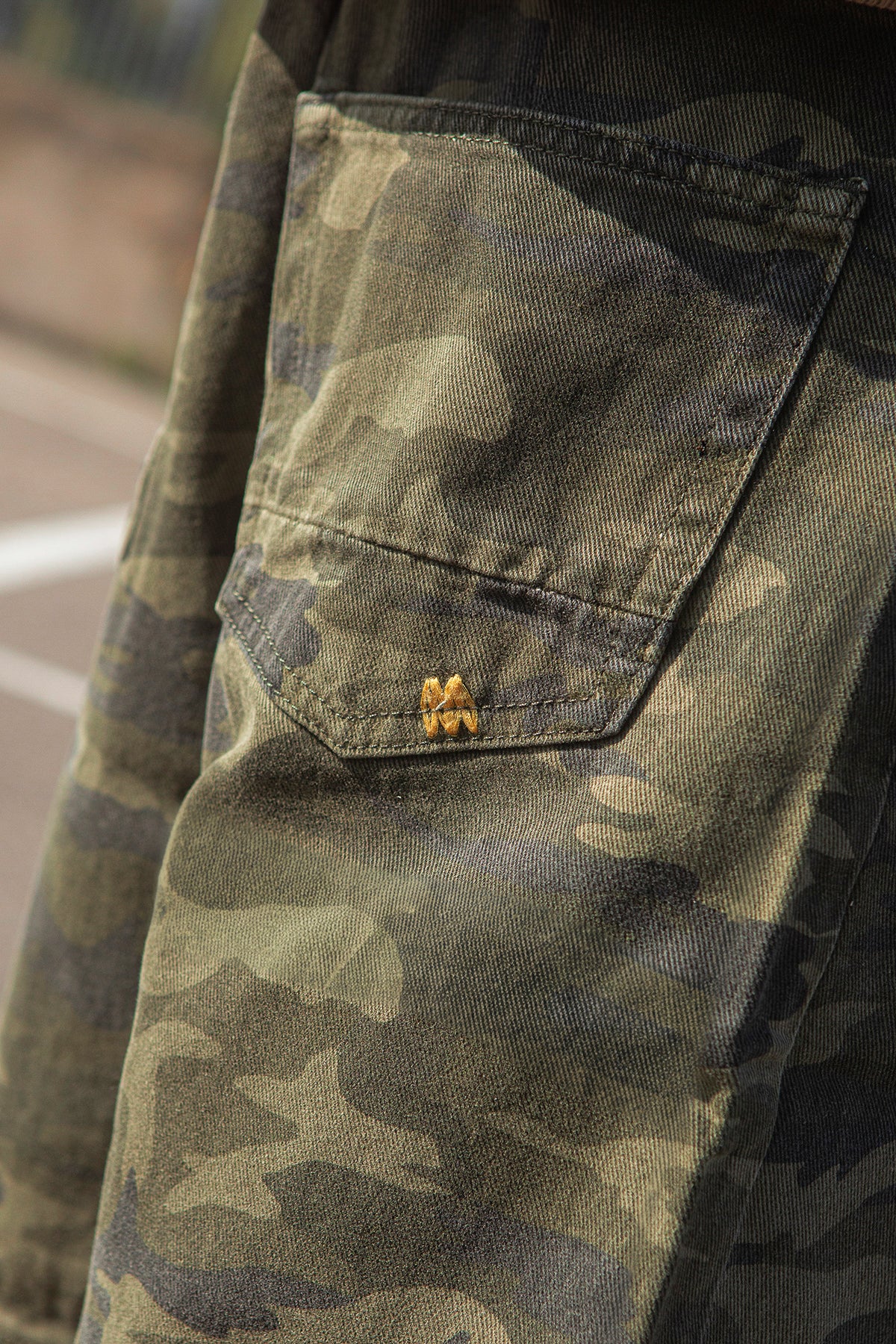 Camouflage pants with a brand logo on the pocket against a blurred background