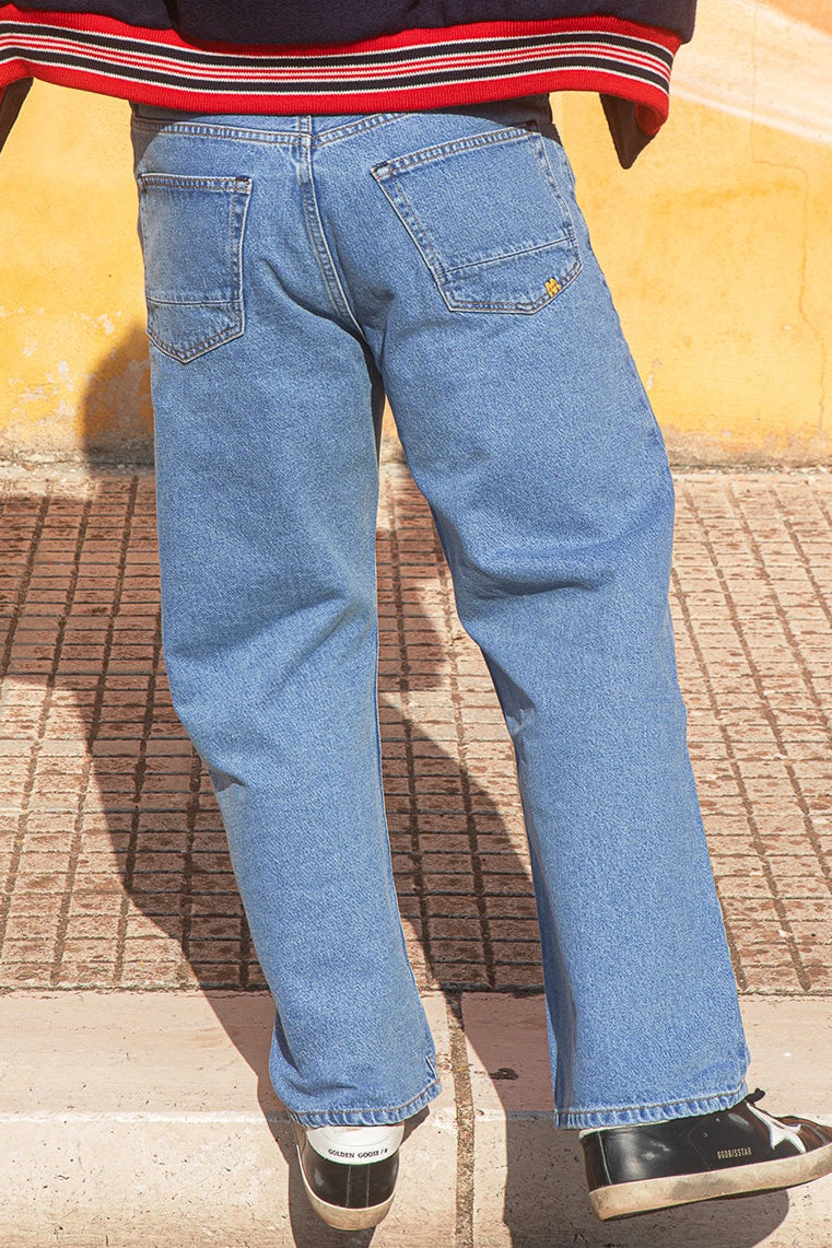 Person wearing blue jeans and a striped shirt with a yellow wall in the background