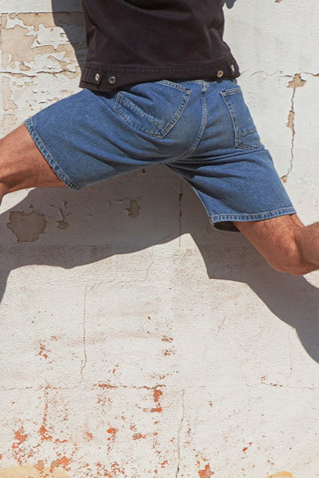 Person climbing a textured wall with a mural of a face.