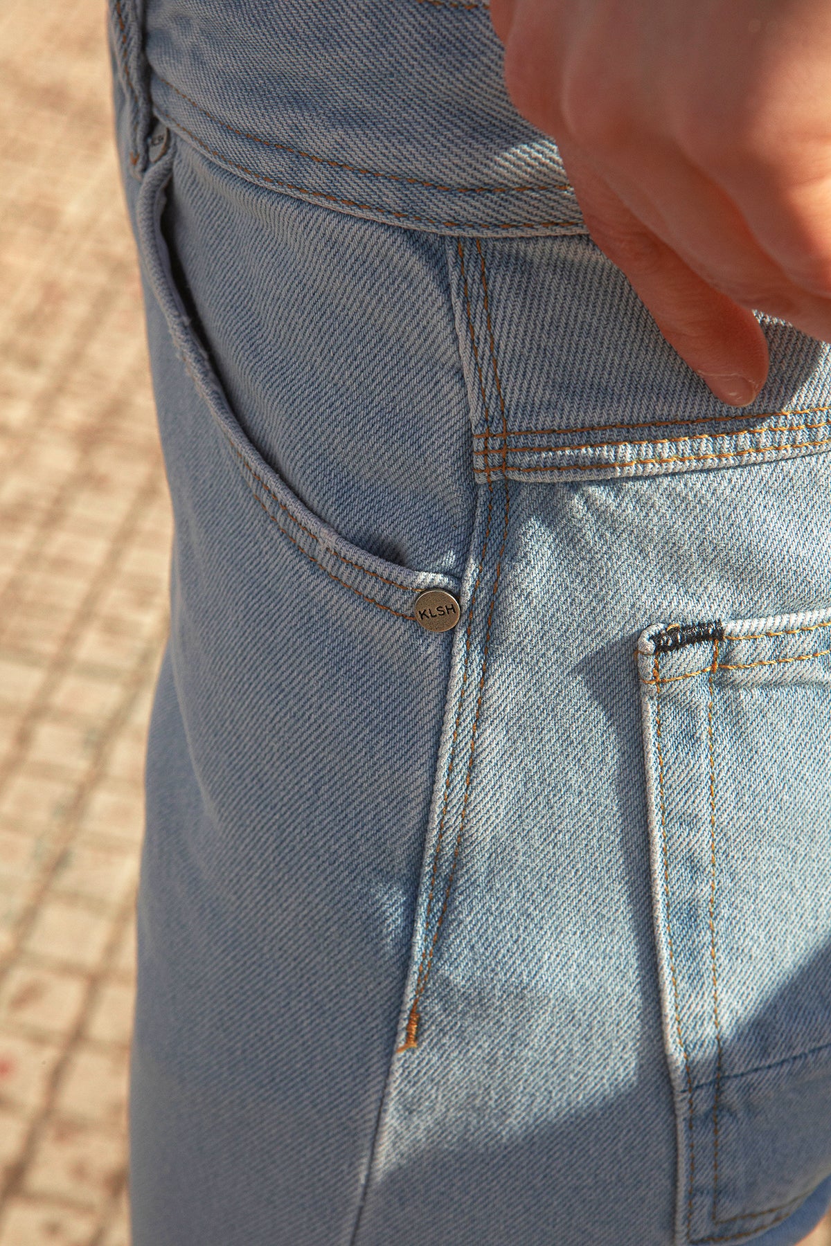 Close-up of MORIS slim-fit jeans with a button and pocket on a blurred background