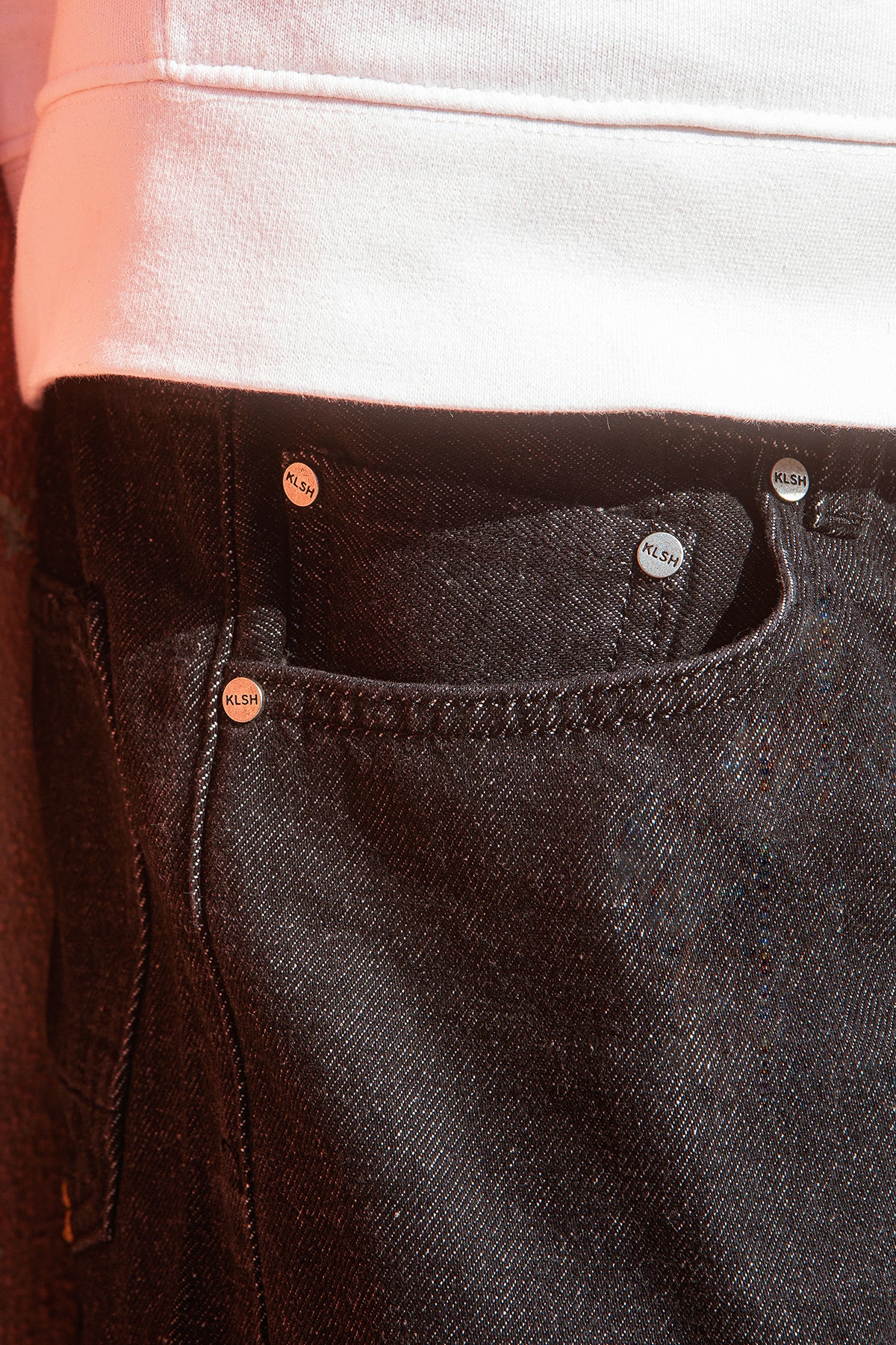 Close-up of black jeans with visible stitching and buttons.