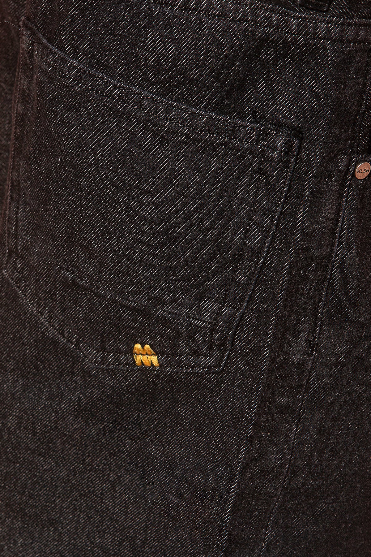 Close-up of dark denim fabric with a brand logo on a pocket