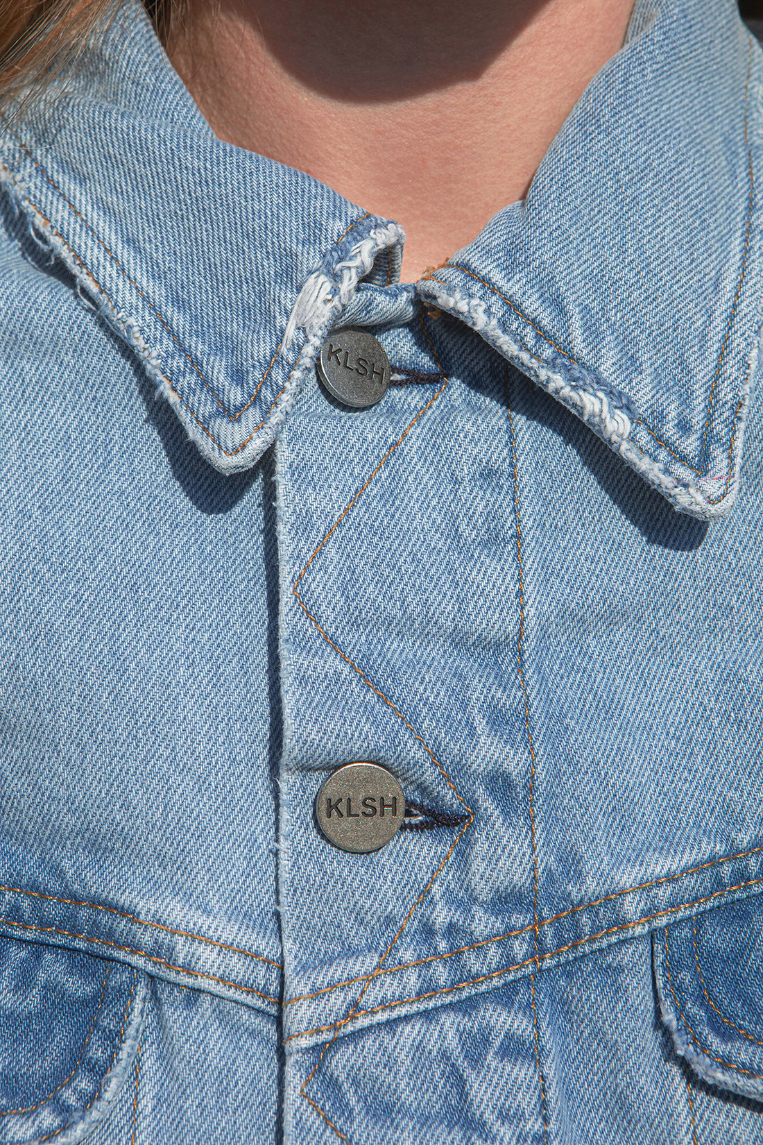 Person wearing a denim outfit standing against a textured wall.