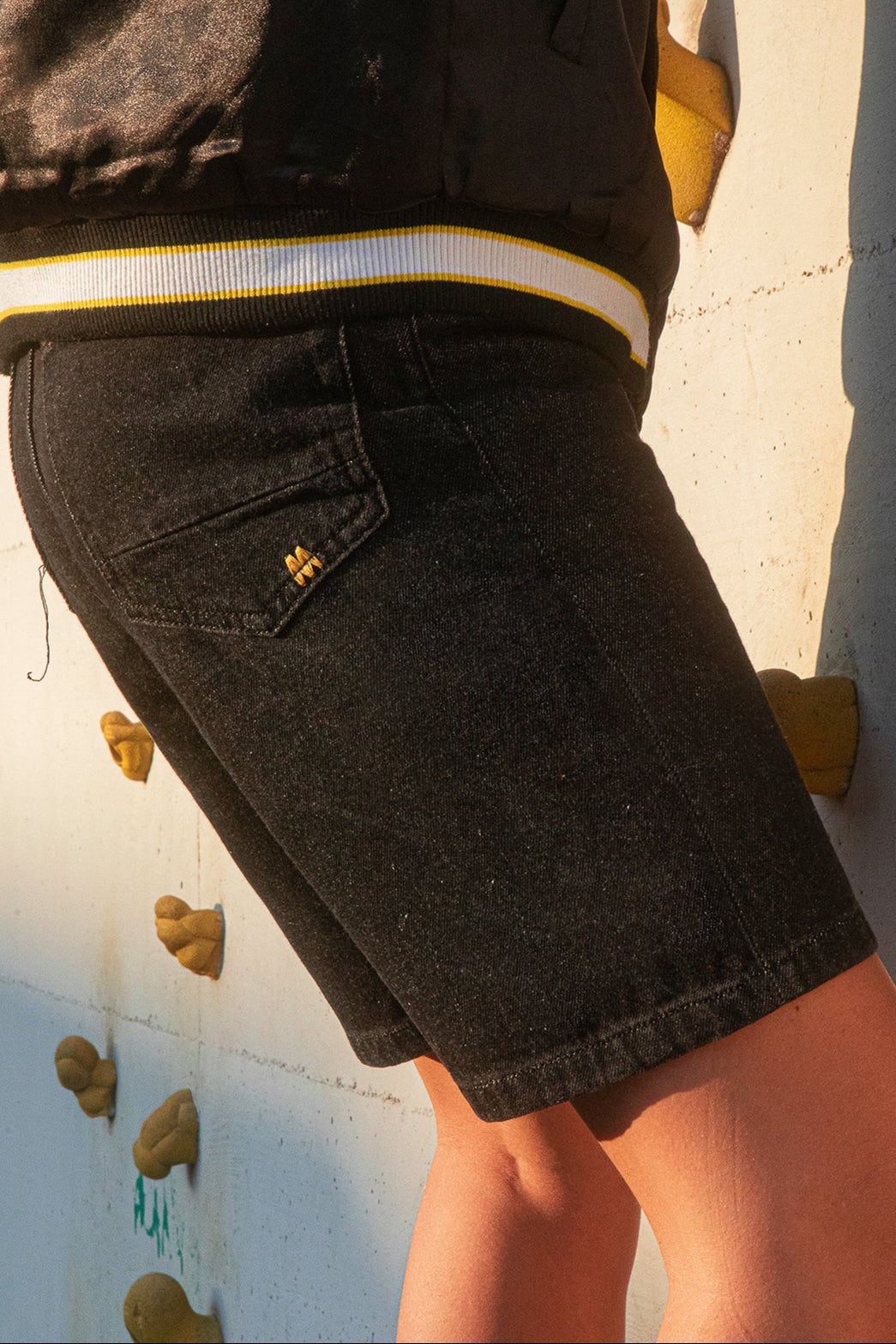 Person wearing black shorts with a logo on a climbing wall background