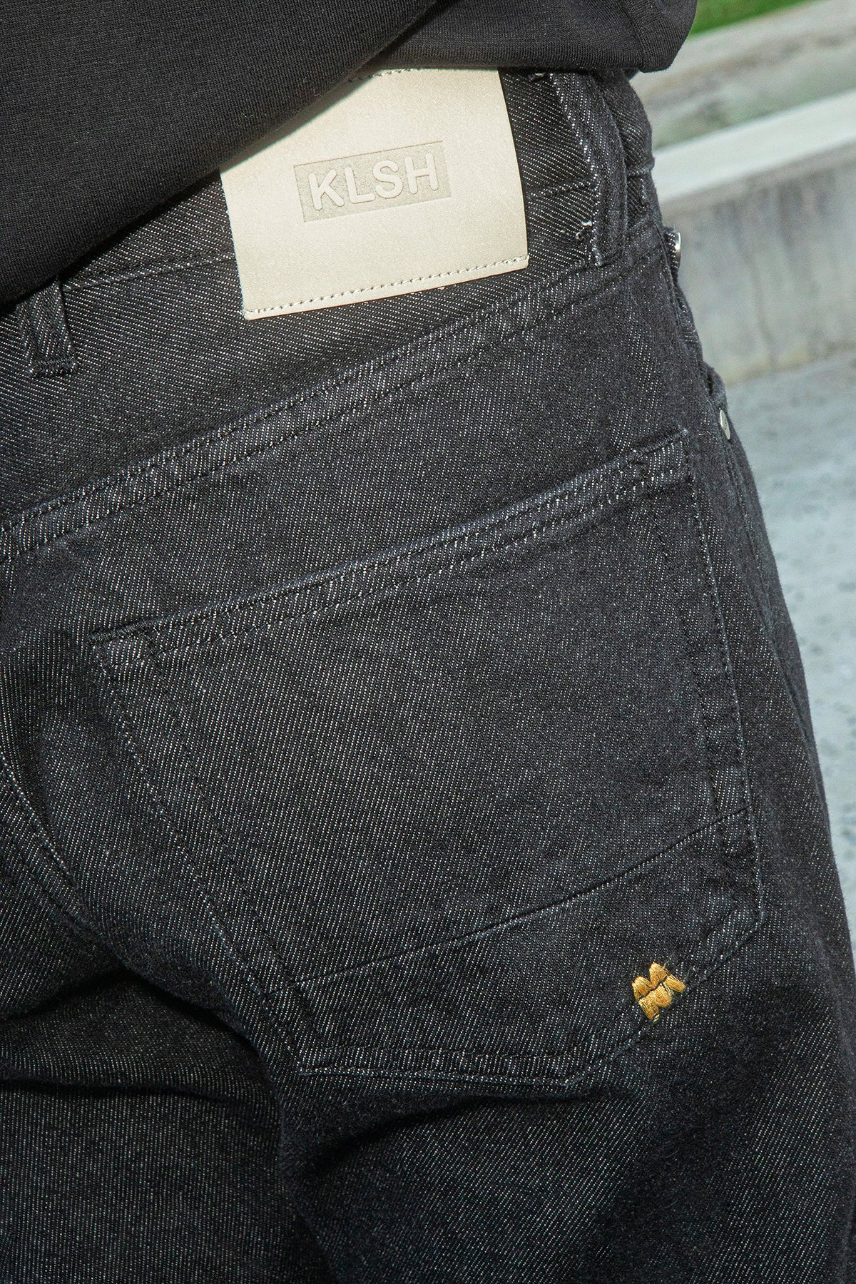 Black pants with a visible brand label on the back pocket.
