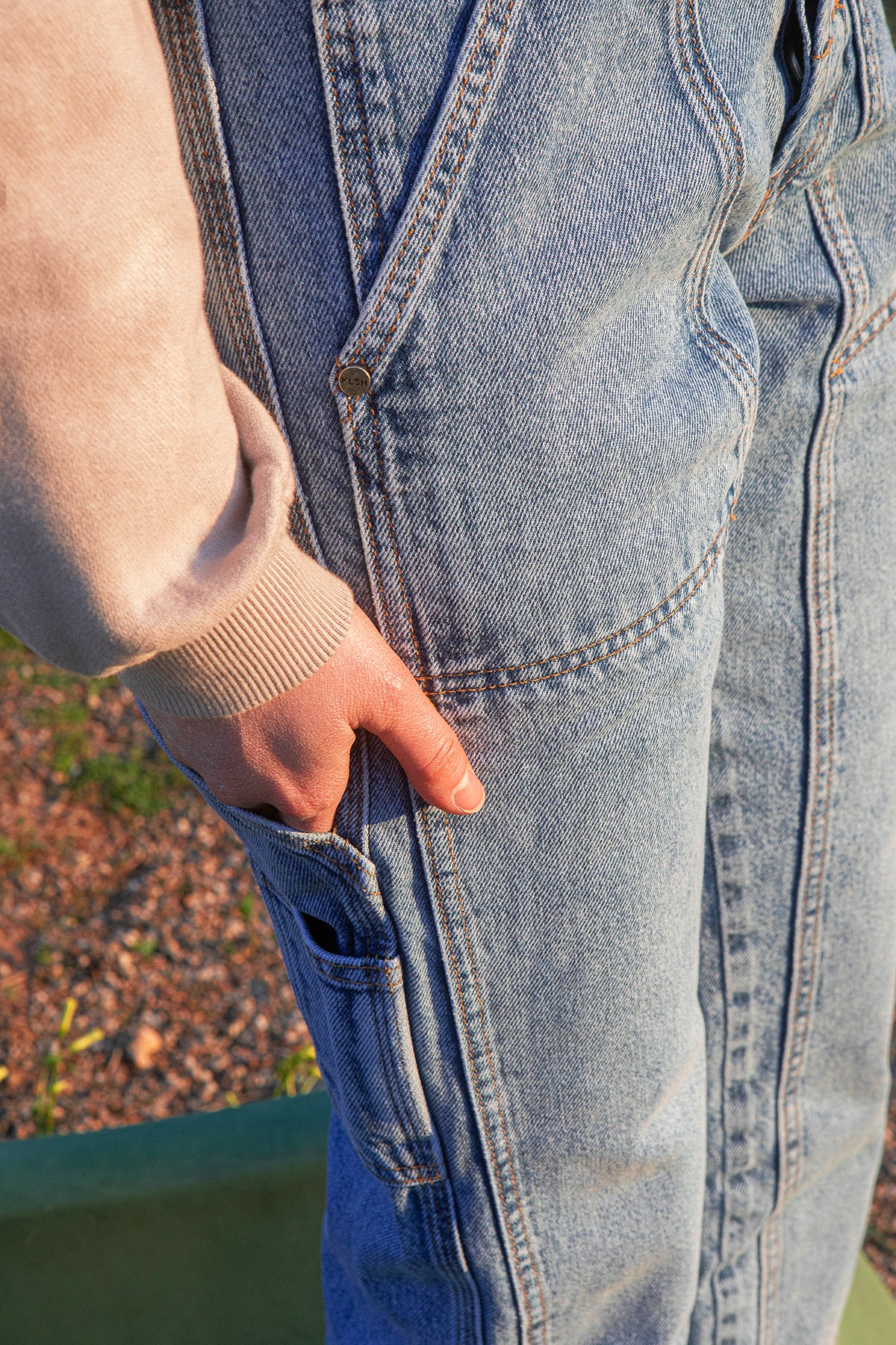 Close-up of a person wearing faded blue jeans with a blurred background