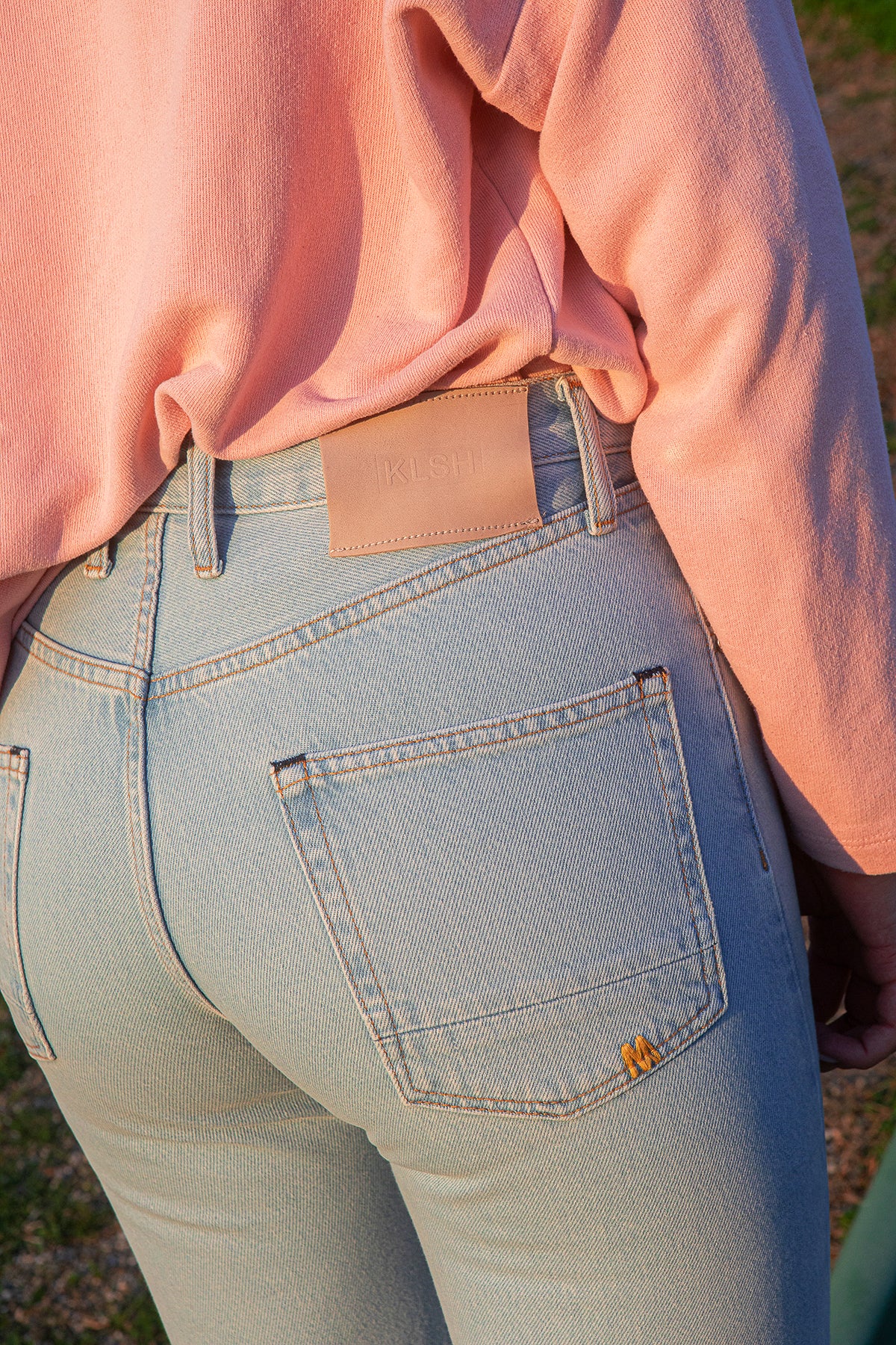 KLSH clear sky jeans with a pink shirt worn by a person outdoors