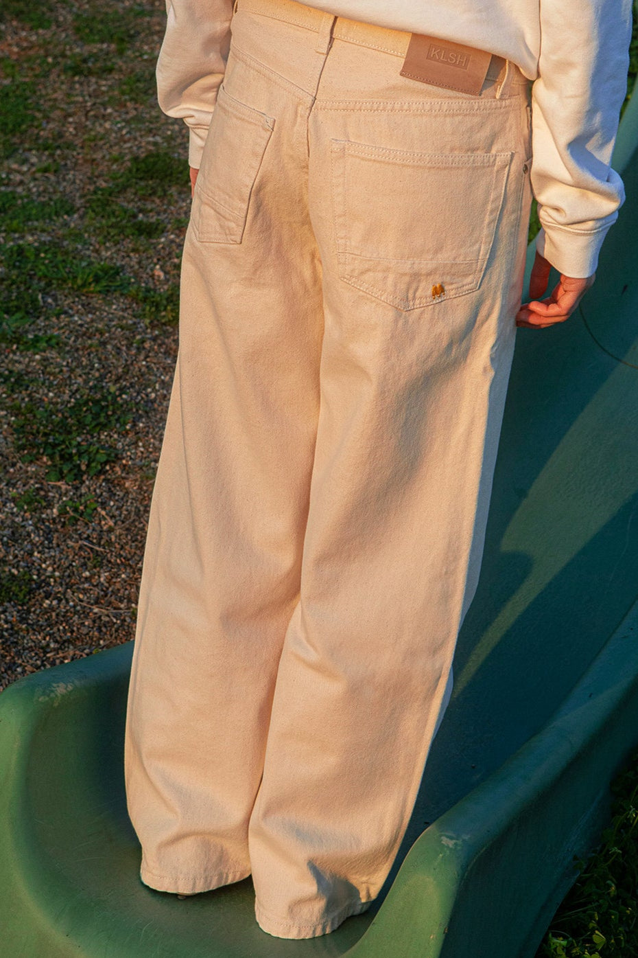 BOSTON Wide flare pants worn by a person standing on a green surface with a blurred background