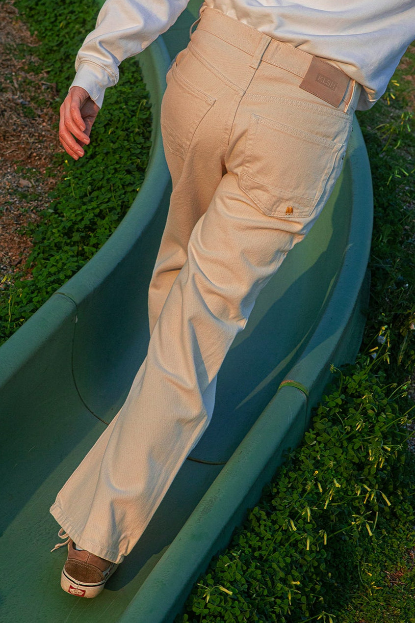Person wearing beige pants and a white shirt on a green slide